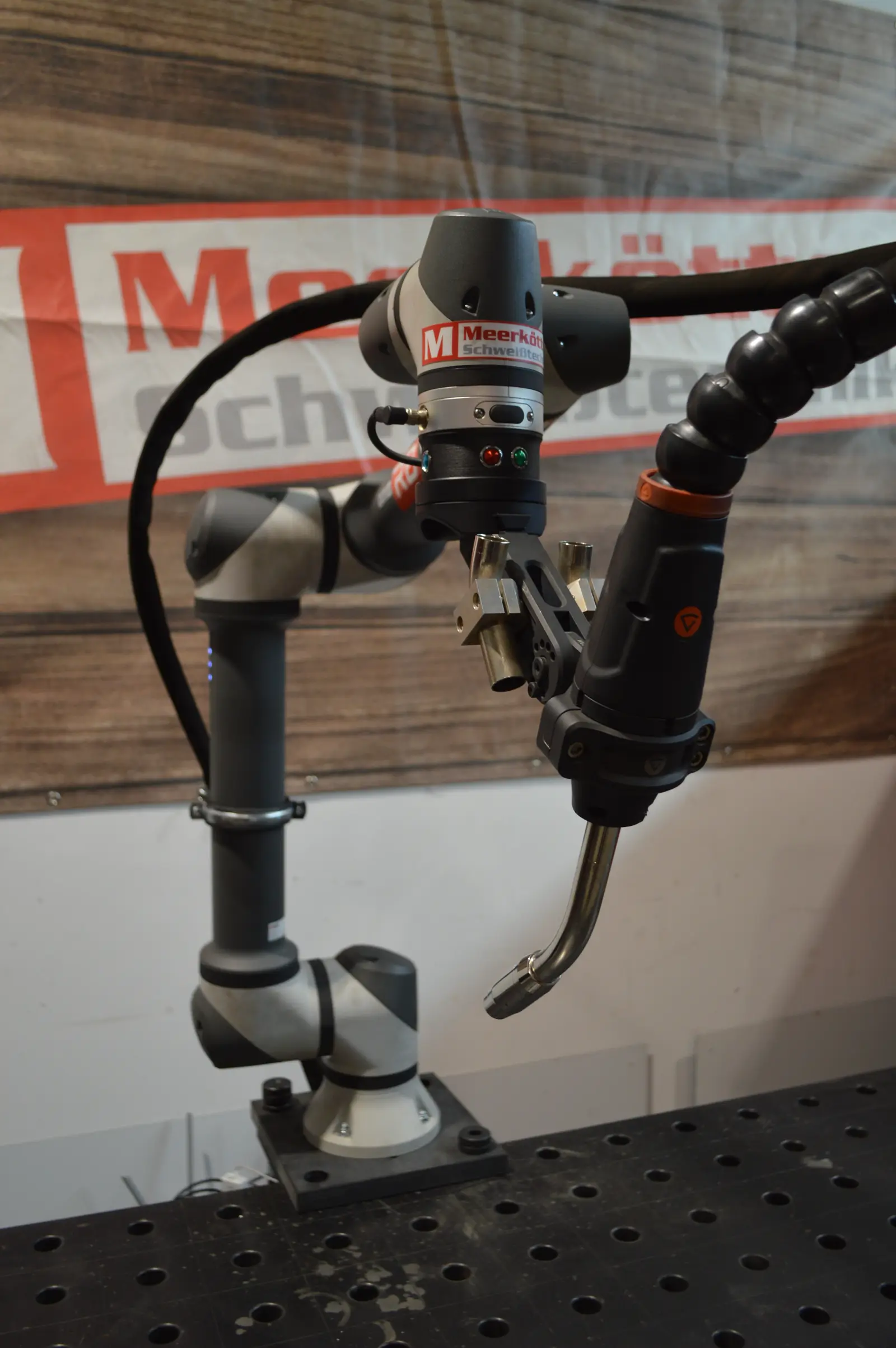 Schweißbrenner an einem Roboterarm über einem Schweißtisch