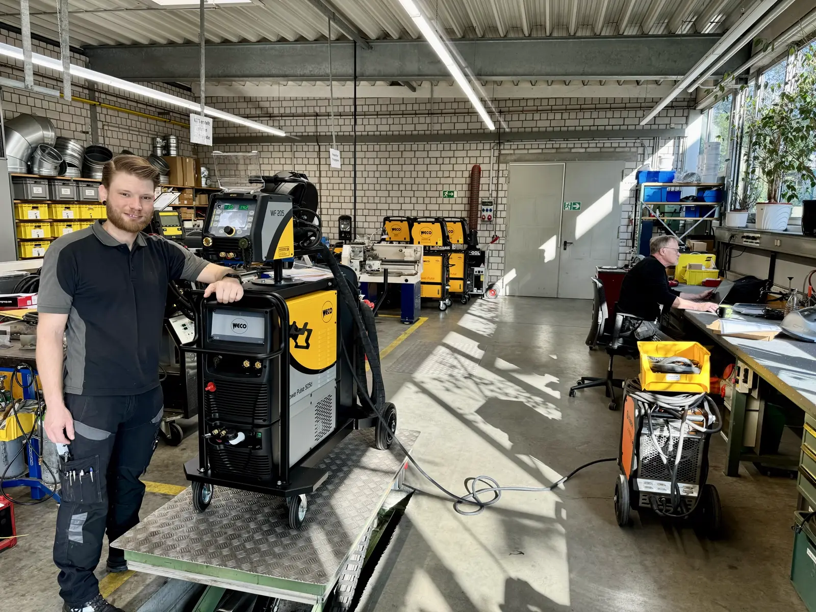Servicetechniker eines SCHWEISS-PROFIS neben einer Schweißstromquelle mit Drahtvorschubgerät in der Werkstatt
